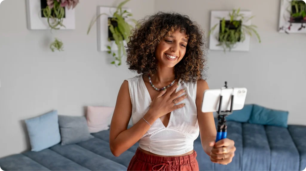 Creadora de contenido graba un video con su smartphone en un trípode para redes sociales
