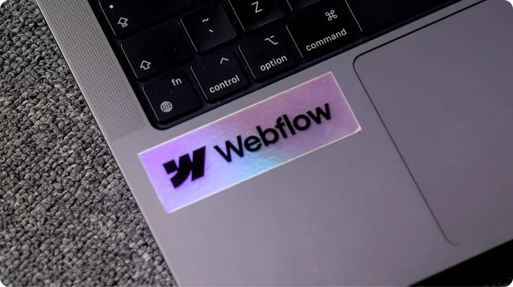 Logotipo de Webflow, plataforma no-code para construir sitios web, en una laptop