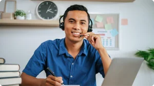 Instructor con auriculares y micrófono toma notas frente a una laptop durante una sesión en vivo